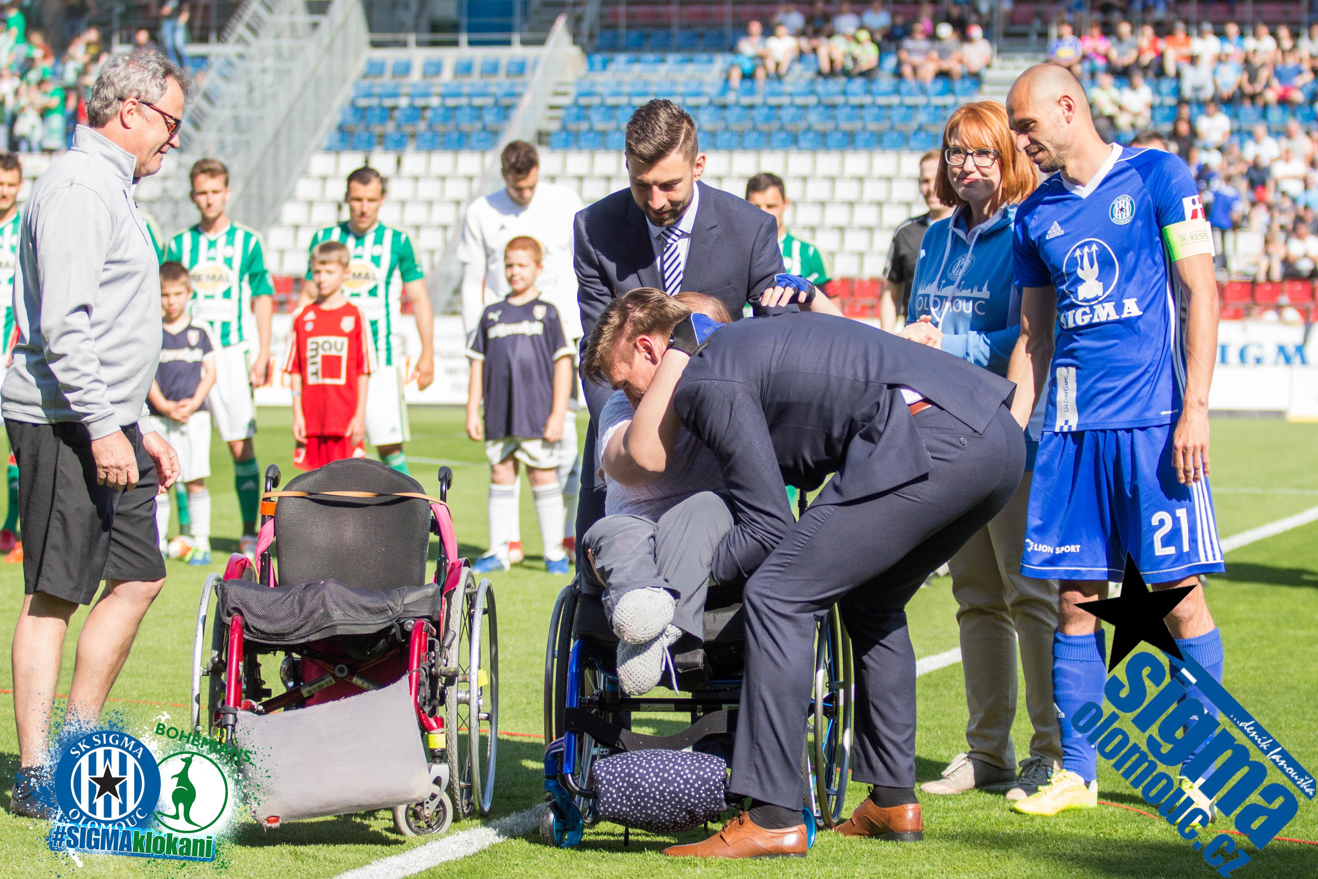 Aleš Škerle pomáhá s přenosem do nového kolečkového křesla fanynce, jež na toto hráči přispěli vysokou částkou